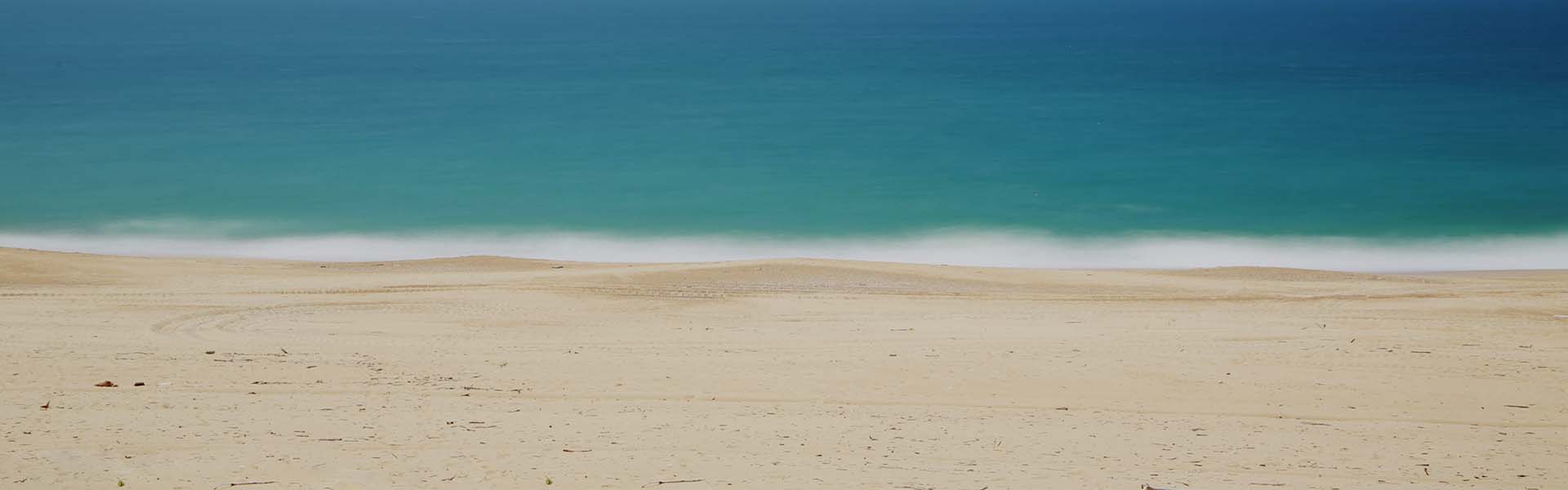 Golden sand and clear turquoise water on a beach in Ios
